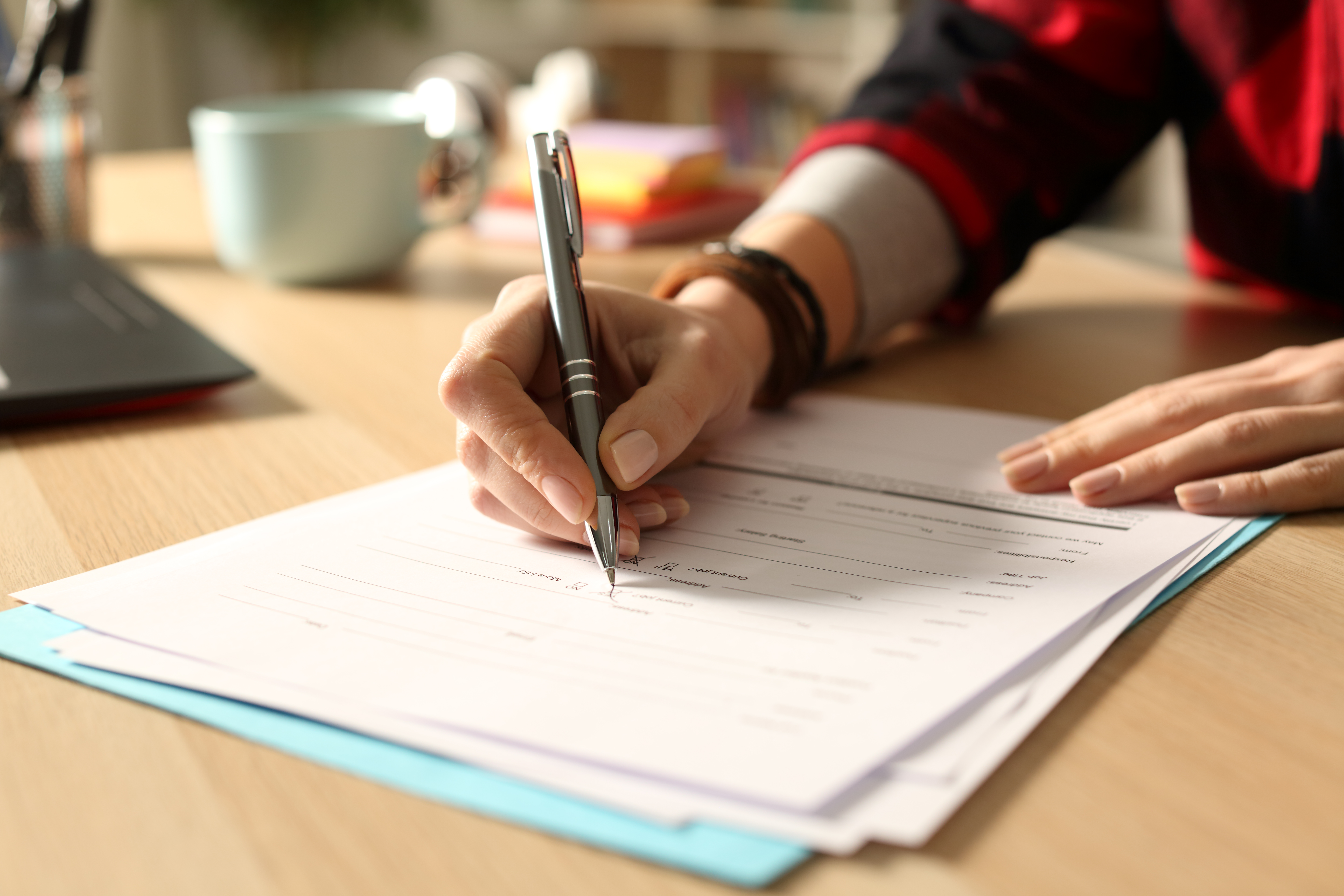 Close up of student girl hand filling out form on a desk at home at night